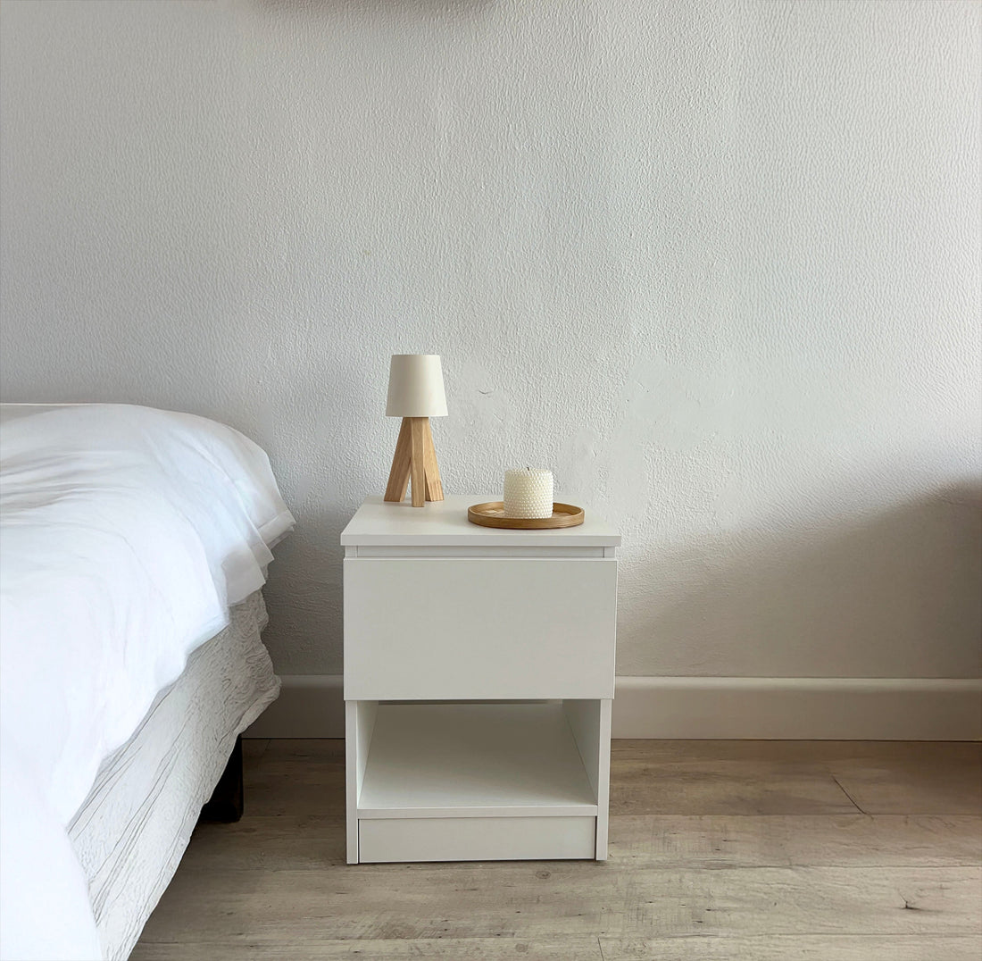 Table de chevet blanche Beetle Wood avec lampe et bougie à côté d'un lit, une idée de cadeau pour la chambre