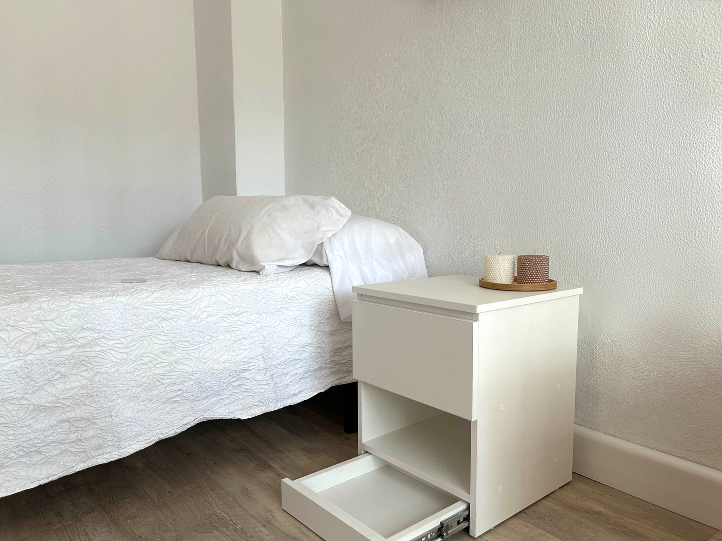 Mesita de noche blanca Beetle Wood con compartimento secreto integrado y apariencia convencional en ambiente de habitacion con cama al lado y con compartimento secreto frontal abierto
