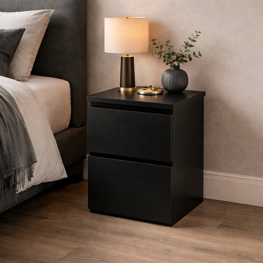 mesita de noche negra moderna junto a cama con lámpara y decoración en dormitorio elegante